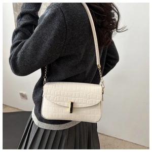 Detailed view of cream crocodile embossed texture and metallic buckle on underarm bag
