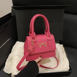 Elegant fuchsia small crossbody bag with golden bow and chain strap in a black gift box