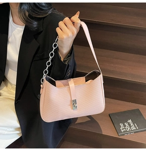 Detalle de bolso baguette rosa texturizado con correa de cadena plateada y cierre de metal