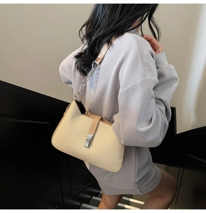 Detalle de bolso beige con textura de sarga y cadena plateada usado por la modelo