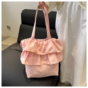 Dettaglio della borsa tote in tela rosa con balze a strati e tracolla abbinata