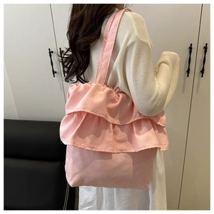 Vista laterale della borsa tote rosa con volant indossata dal modello che mostra la taglia