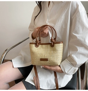 Détail d'un sac à main en paille tressée avec poignées en cuir marron et bandoulière