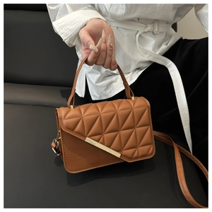 Macro detail of brown quilted leather bag featuring a gold metal buckle and triangle stitching