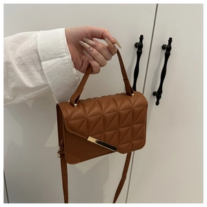 Detail of brown quilted shoulder bag with matte leather and gold metal buckle