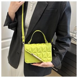 Detailed view of neon green quilted crossbody bag with gold buckle on black suit