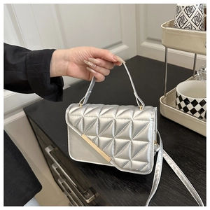 Detail of silver quilted square bag with gold metal bar and textured finish