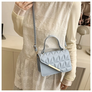 Close-up of light blue quilted shoulder bag with matte gold hardware and diamond pattern
