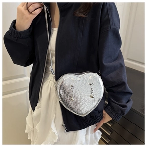 Detail of silver crocodile pattern heart-shaped crossbody bag with metal chain accents
