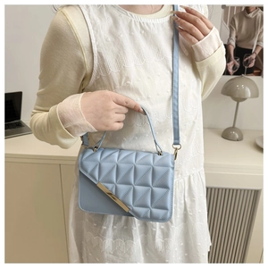 Detail of light blue quilted crossbody bag with gold metal trim and adjustable strap