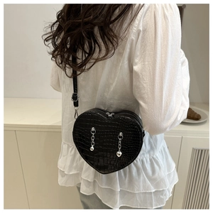 Close-up of heart-shaped crocodile pattern bag with silver chain details and metal charms