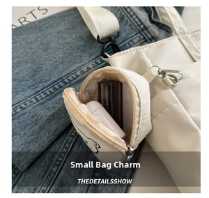 Close-up of white canvas mini bag charm with cute bear print and silver metal hook