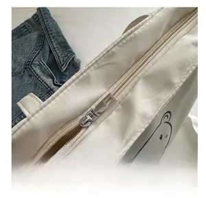 Detail view of smooth nylon zipper and metal puller on white canvas tote bag