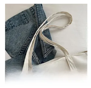 Detail of white canvas tote bag featuring reinforced dual stitching and metal magnetic clasp