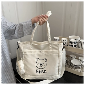 Detail of white canvas tote with cartoon bear print and matching round coin purse charm