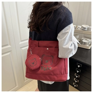 Close-up of a burgundy canvas tote bag with a cute bear print and round coin purse charm