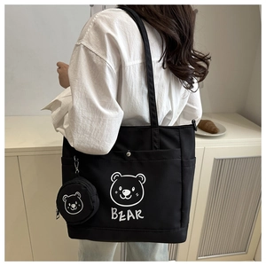 Close-up of black canvas tote bag with cartoon bear print and matching round coin purse