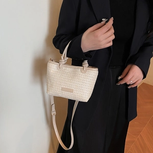 Minimalist straw woven handbag with leather strap shown in a chic outfit styling