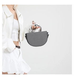 Detail of grey textured fabric saddle bag featuring a unique liquid silver metal handle