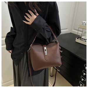 Détail d'un sac seau marron avec boucle métallique verticale et texture en similicuir