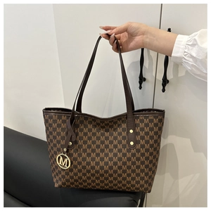 Macro detail of brown tote bag featuring M letter jacquard and golden metal charm