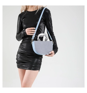Light blue saddle bag with textured surface and silver round metal handle worn by model