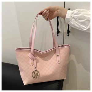 Detailed view of pink tote bag with letter patterns and signature gold M pendant