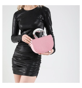 Pink glitter saddle bag with heart-shaped silver handle shown with fashion model