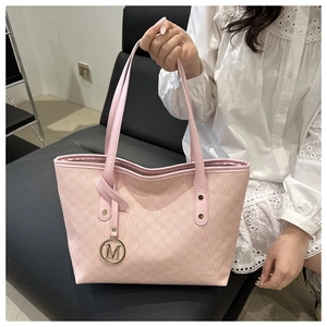 Detail of pink monogram tote bag featuring golden M logo charm and rivet hardware
