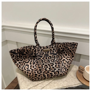 Macro detail of leopard print tote bag featuring sturdy handles and gold logo hardware