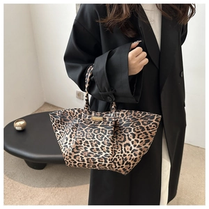 Detail of leopard print tote bag with gold metal buckle on minimalist background