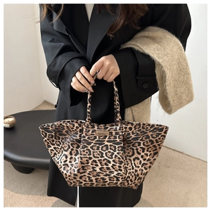 Close-up of leopard print tote bag featuring a sleek gold metal buckle and long handles