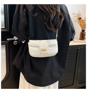 Rear view of model wearing a white quilted crossbody bag with gold turn-lock closure