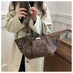 Macro shot of the stylish leopard print tote bag with a polished gold metallic logo plate