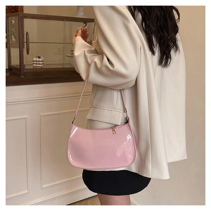 Chic pink patent leather hobo bag worn by a model in an elegant cafe setting