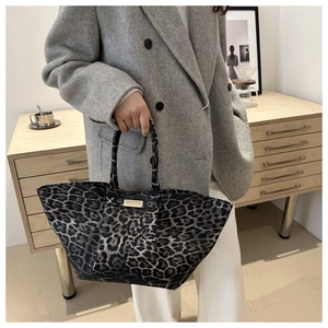 Detail of leopard print tote bag with metal plaque and premium fabric texture