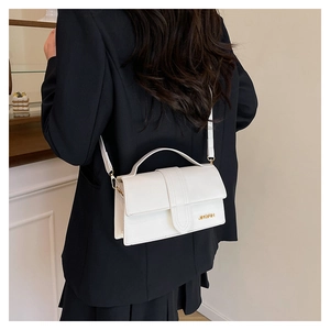 Close-up of a white minimalist rectangular flap bag with golden metallic logo detail