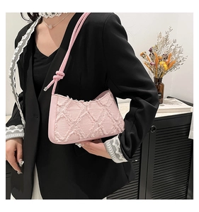 Detail of pink quilted denim crescent bag with frayed edges and knotted shoulder strap