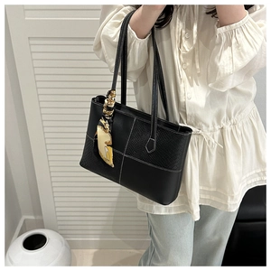 Détail du sac cabas noir avec empiècements texturés et foulard en soie sur la poignée