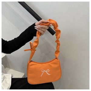 Detail of orange nylon underarm bag with white bow embroidery and ruched strap