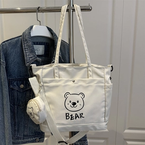 White canvas tote bag with black bear print and a matching small round coin purse charm