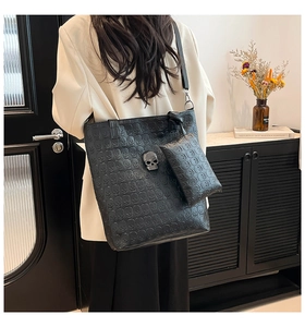 Detailed close-up of black tote bag with skull embossed pattern and gothic metal stud