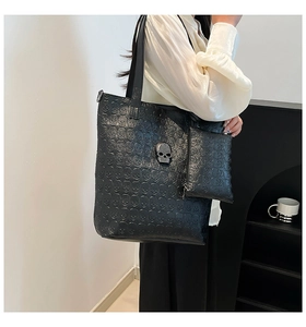 Detail of black skull embossed tote bag with studded skull charm for women fashion