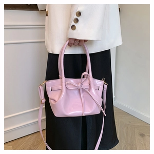 Detail of pink patent leather bag with bow knot and glossy finish on a white background