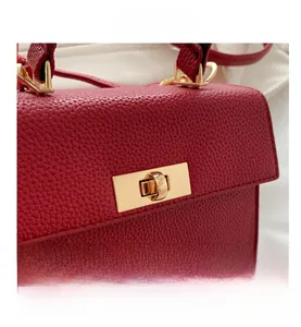Close-up of red lychee pattern leather handbag with elegant gold metal twist lock