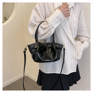 Close-up of glossy black bow bucket bag featuring polished faux leather and elegant details
