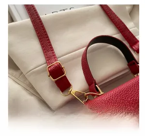 Detail of red litchi leather bag showing gold adjustable buckle and shoulder strap