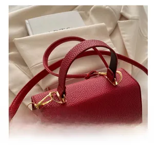 Detail of red pebbled leather handbag featuring gold hardware locks and a textured finish