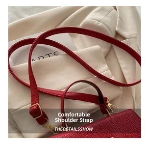 Macro view of red lychee grain leather handbag with gold buckle and adjustable strap