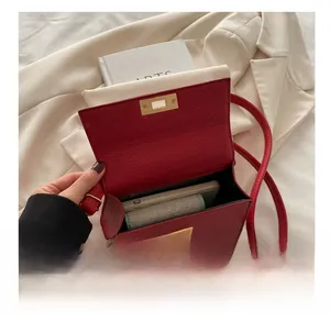 Detail view of open dark red lychee leather crossbody bag with gold metal lock and phone